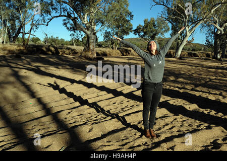 A young woman enjoys the morning sunshine at Roe Creek, Honeymoon Gap in the MacDonnell Ranges, Northern Territory, Australia Stock Photo