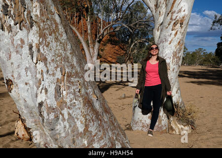 A young woman enjoys the morning sunshine at Roe Creek, Honeymoon Gap in the MacDonnell Ranges, Northern Territory, Australia Stock Photo