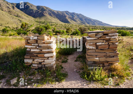 Wire gate in a stone wall opens toward a whitewashed stone building under shady trees at Frijole Ranch, Guadalupe Mountains National Park, Texas. Stock Photo