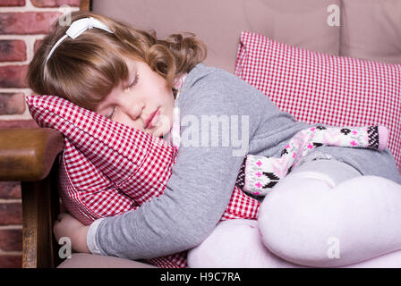 Girl in dress sleeps on the sofa with a pillow Stock Photo