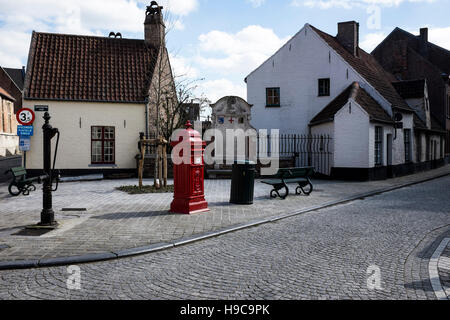 A hand water pump, post box and bench in a cobbled street in Bruges Belgium Stock Photo