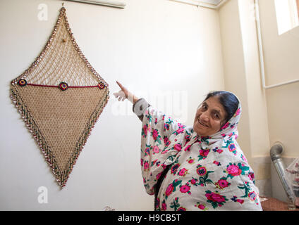 Portrait of an iranian woman wearing traditional floreal chador and showing a lucky charm, Natanz county, Abyaneh, Iran Stock Photo