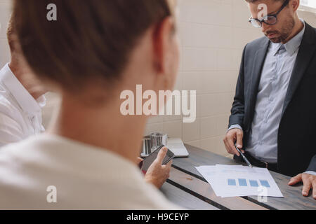 Young male executive explaining a financial plan to coworkers at meeting. Business people discussing financial plan in office. Stock Photo