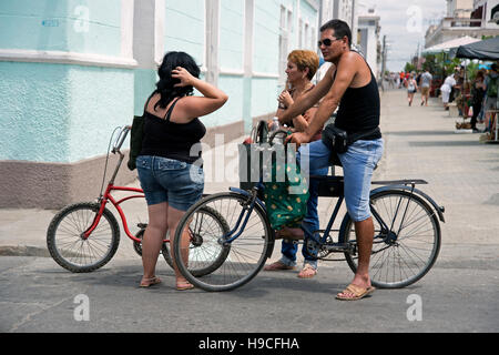 Residents of Cienfuegos Cuba sitting on their bicycles stop for a chat along one of the many colonial streets Stock Photo