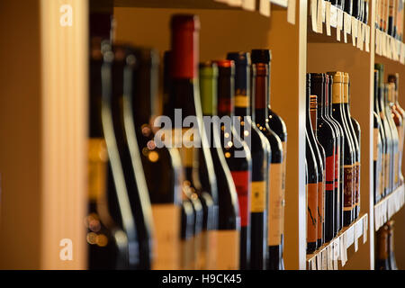 Wine bottles on wooden shelf in wine store Stock Photo
