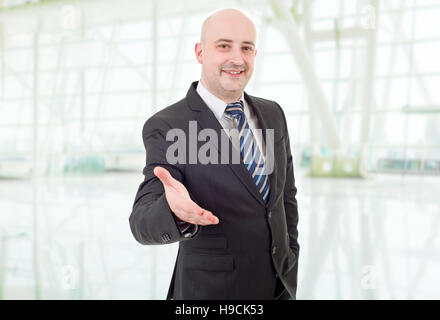 businessman in suit offering to shake the hand, at the office Stock Photo