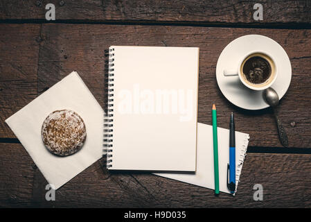 Blank page of notepad on the wooden table. Pen, pencil, cup od coffee and honey-cake. Stock Photo