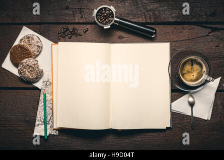 Blank pages of notepad on the wooden table, Coffee beans in filter holder, cup of espresso and three honey-cakes Stock Photo