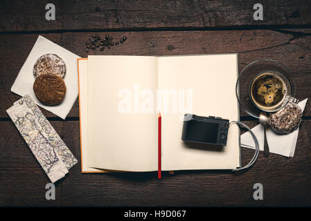 Compact camera on blank page of notepad on the wooden table, honey-cakes, red pencil and cup of espresso Stock Photo