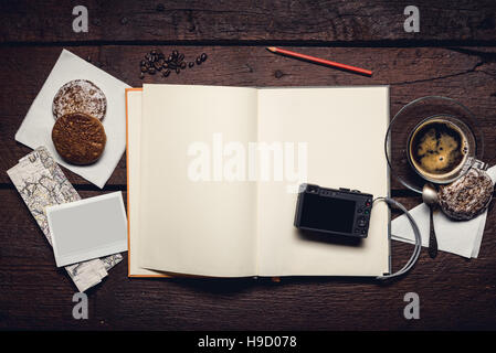Compact camera on blank page of notepad on the wooden table, honey-cakes, red pencil and cup of espresso, blank photograph. Stock Photo