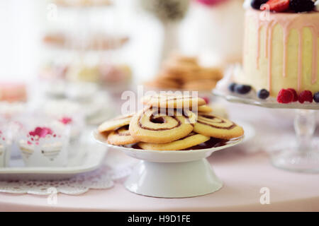 Spiral cookies, cake and cupcakes laid on table. Stock Photo
