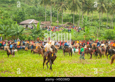 Horsemen at the Pasola, an annual battle where tribes throw spears to spill blood and fertilize the land to ensure a good harvest, on Sumba in Indones Stock Photo