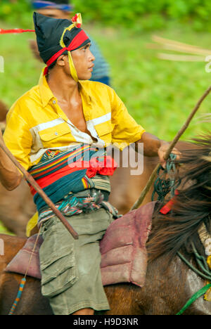 Horsemen at the Pasola, an annual battle where tribes throw spears to spill blood and fertilize the land to ensure a good harvest, on Sumba in Indones Stock Photo