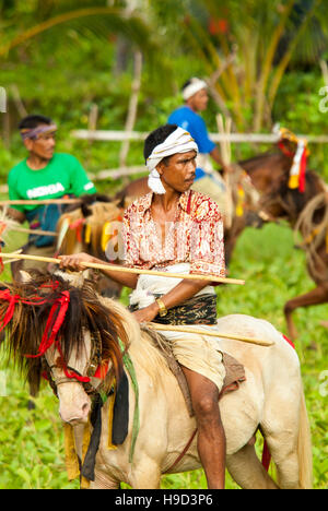 Horsemen at the Pasola, an annual battle where tribes throw spears to spill blood and fertilize the land to ensure a good harvest, on Sumba in Indones Stock Photo