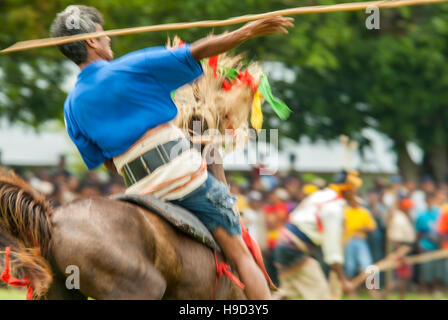 Horsemen at the Pasola, an annual battle where tribes throw spears to spill blood and fertilize the land to ensure a good harvest, on Sumba in Indones Stock Photo