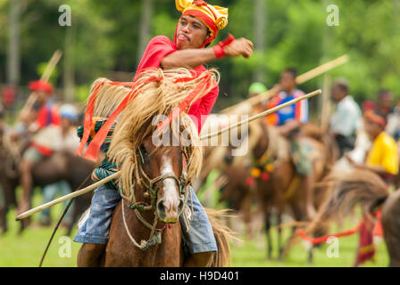 Horsemen at the Pasola, an annual battle where tribes throw spears to spill blood and fertilize the land to ensure a good harvest, on Sumba in Indones Stock Photo