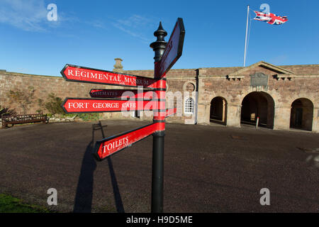 Fort George Scotland. Visitor direction signpost, with Fort George’s main entrance and guardrooms in the background. Stock Photo