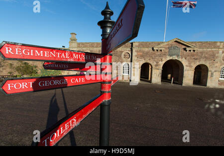 Fort George Scotland. Visitor direction signpost, with Fort George’s main entrance and guardrooms in the background. Stock Photo