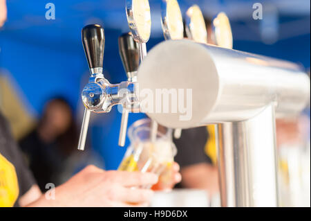 Barman hand at beer tap pouring a drought lager beer serving in a restaurant or pub. Stock Photo