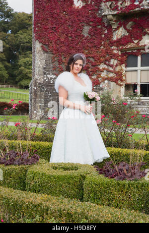 Bride has photos taken in formal garden during autumn with box topiary Stock Photo