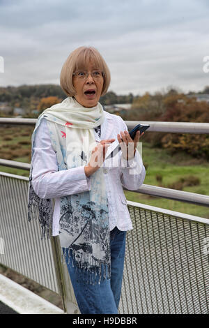 Elderly Japanese woman recieves a shocking text message on her smart phone Stock Photo