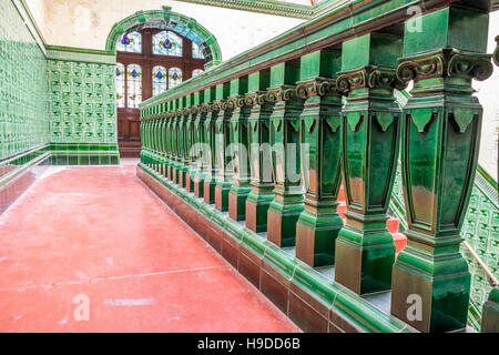 an upper level balcony made from green tiles and a green handrail with a red floor. Stock Photo