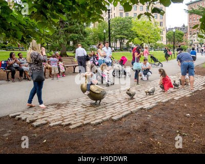Children play on bronze sculptures of a duck and ducklings created by Nancy Schon in memory of the book 'Make Way for Ducklings' by Robert McCloskey. Stock Photo