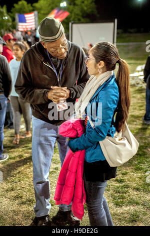 An African American spokesman talks with a Hispanic visitor as  multiracial faithful gather in Mission Viejo, CA, for an nighttime open air prayer service as part of The National Day of Prayer, an annual day of observance held on the first Thursday of May Stock Photo