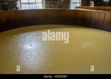 Mash in oak barrel fermentation tanks inside stone distillery. Stock Photo