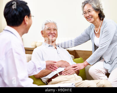 senior asian patient being taken care of by his wife and a family doctor Stock Photo