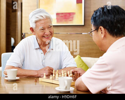 two asian men playing chess game at home Stock Photo
