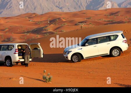 Four-wheel drives (Nissan Patrol and Toyota Land Cruiser) in the desert, Abu Dhabi Emirate, UAE. The mountains in the distance are in Oman. Stock Photo