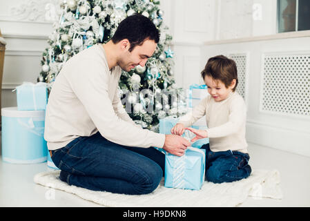 Father and son unwrapping a present lying on the floor Stock Photo