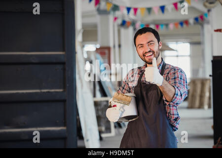 Handyman using brush in his workshop with thumb up Stock Photo