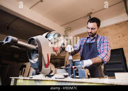 Young craftsman in uniform working at carpentry and looking to camera Stock Photo