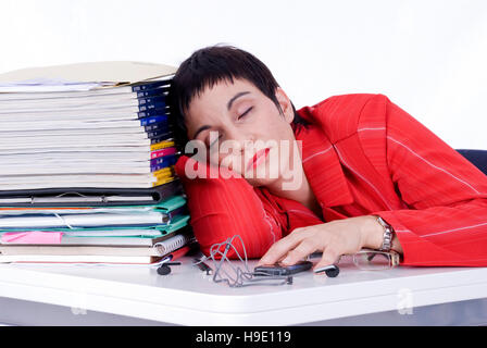 Exhausted businesswoman sleeping next to a pile of files in the office Stock Photo