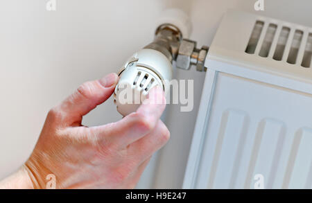 Hand Adjusting Heater Thermostat in winter time Stock Photo