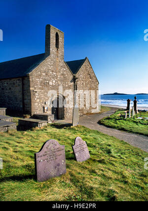 St Hywyn's Norman & Medieval church, Aberdaron, Gwynedd, W end with C12th doorway, view SE to Ynys Gwylan-fawr & Ynys Gwylan-fach (R) Stock Photo