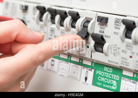 An RCD circuit breaker board displays many switches. Most are in the ON position, but one is switched down to OFF. It is the circuit for the lighting. Stock Photo