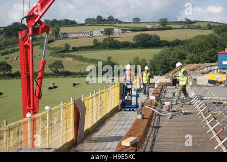 Concrete is pored during the construction of a new road bridge on the A30 in Cornwall. Shows farmland in background. Stock Photo