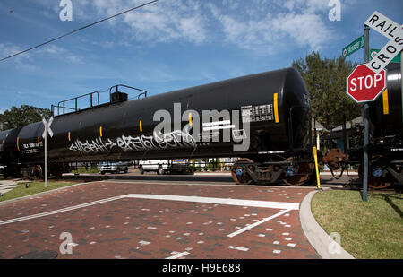 Mount Dora Florida USA -  Railroad freight train hauling liquid carrying trucks passing over unmanned crossing Stock Photo
