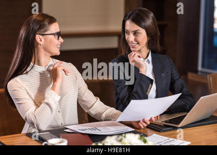 Happy female colleagues smiling to each other in office Stock Photo