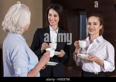 Three colleagues communicating during coffee break at workplace Stock Photo