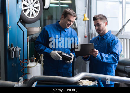 Positive mechanics standing in auto service. Stock Photo