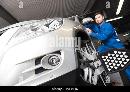 Serious young mechanic adjusting automobile wheel alignment Stock Photo