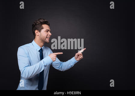 Cheerful businessman pointing aside. Stock Photo