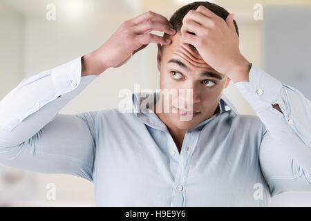 Man checking hairline, in a bathroom Stock Photo