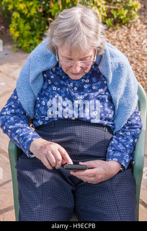 A woman in her 80's using a smart phone in the Uk Stock Photo