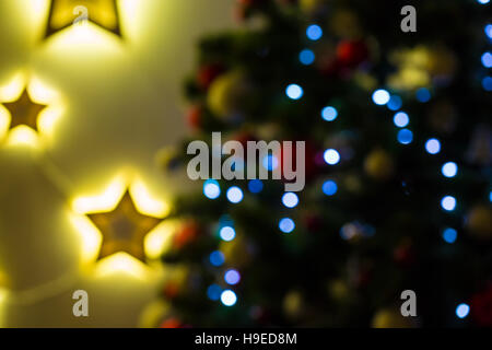 Closeup of Christmas-tree background in the living room of the house with glowing stars on the wall Stock Photo