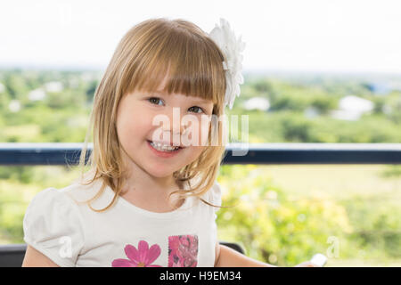 Little girl with flower in hair smiling and happy outdoors Stock Photo